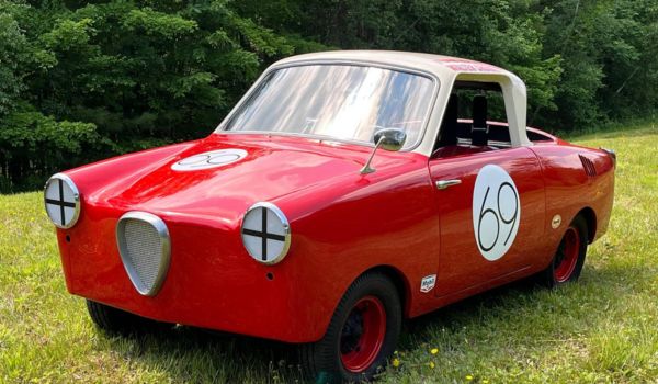 A red 1958 Goggomobil TS 400 microcar with racing number 69, parked in a grassy field